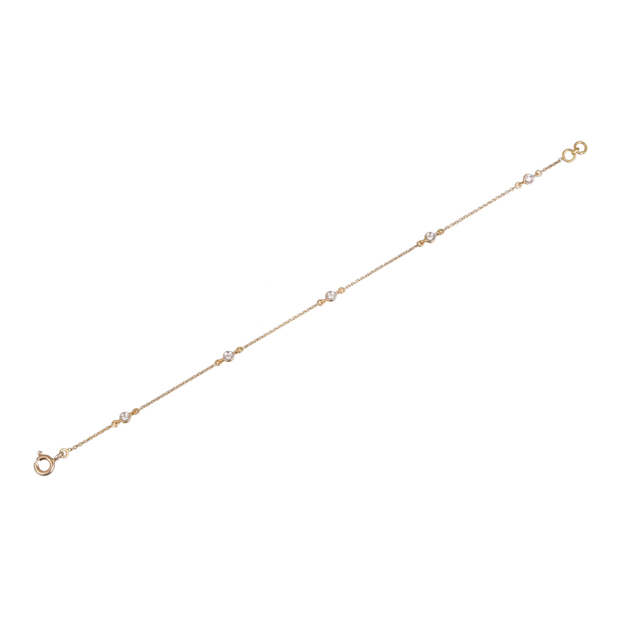 Yellow gold diamond-by-the-yard bracelet laid flat showing full length, five bezel-set round diamonds on fine cable chain with spring ring clasp and adjustable extension ring, white background
