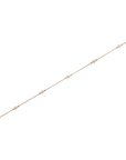 Yellow gold diamond-by-the-yard bracelet laid flat showing full length, five bezel-set round diamonds on fine cable chain with spring ring clasp and adjustable extension ring, white background